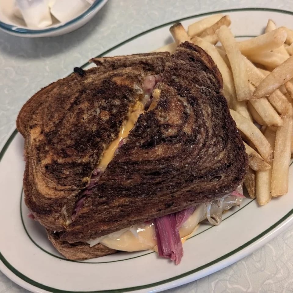 A Reuben sandwich on marbled rye with fries on a white plate at Chef Darrell's Mountain Diner.