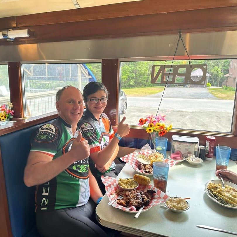 Two happy men in cycling jerseys giving thumbs up while dining at Chef Darrell's Mountain Diner.