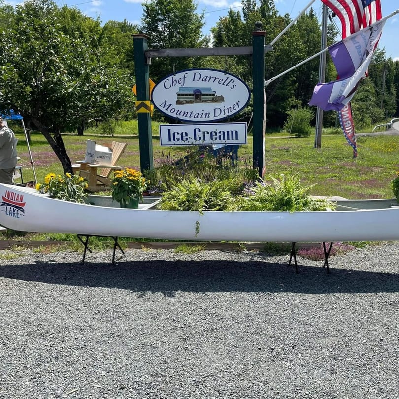 Chef Darrell's Mountain Diner sign and an "Indian Lake" canoe planter filled with flowers.