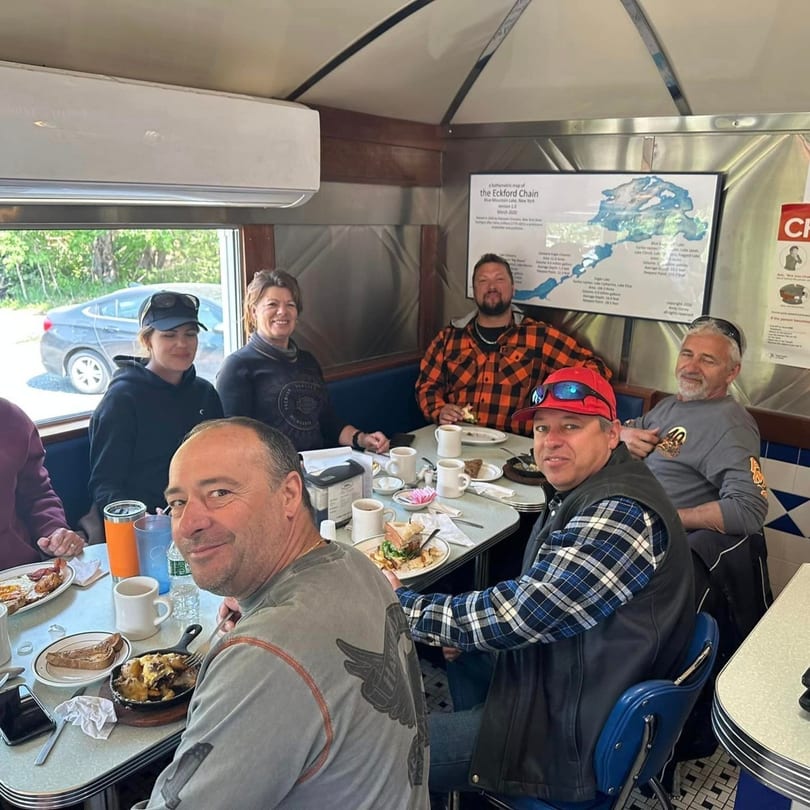 Group of six people enjoying diner food and coffee at Chef Darrell’s Mountain Diner.