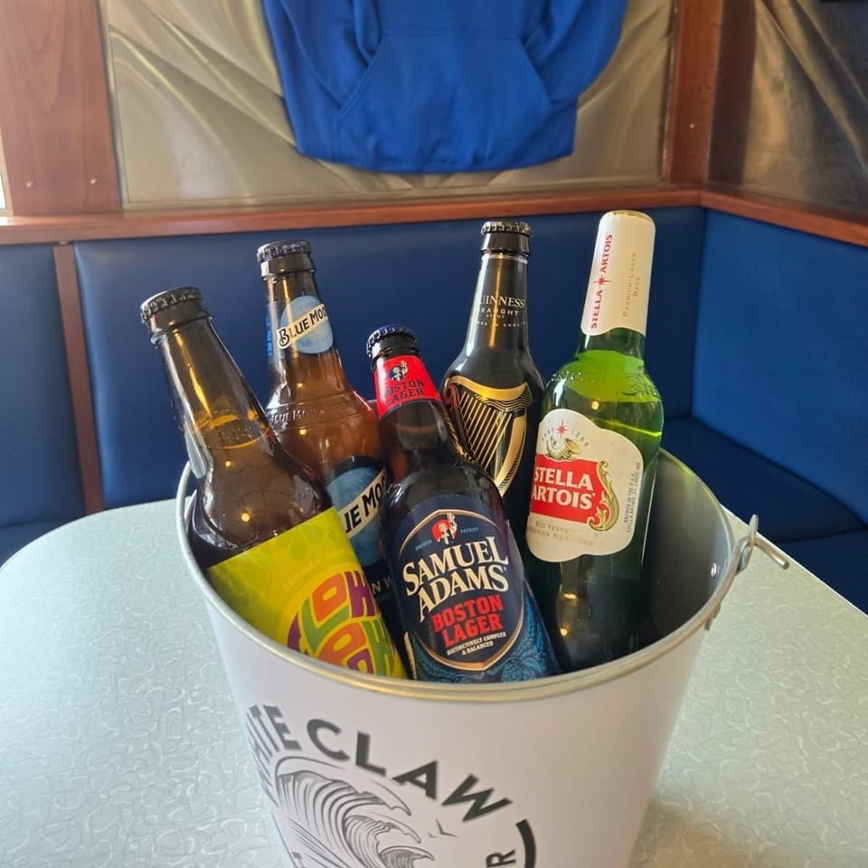 A bucket of assorted beer bottles, including Stella Artois, Samuel Adams, and Guinness, on a diner table.