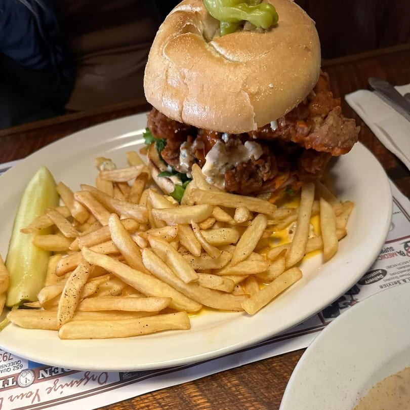 A fried chicken sandwich with pickles and fries on a white plate at Chef Darrell's Mountain Diner.